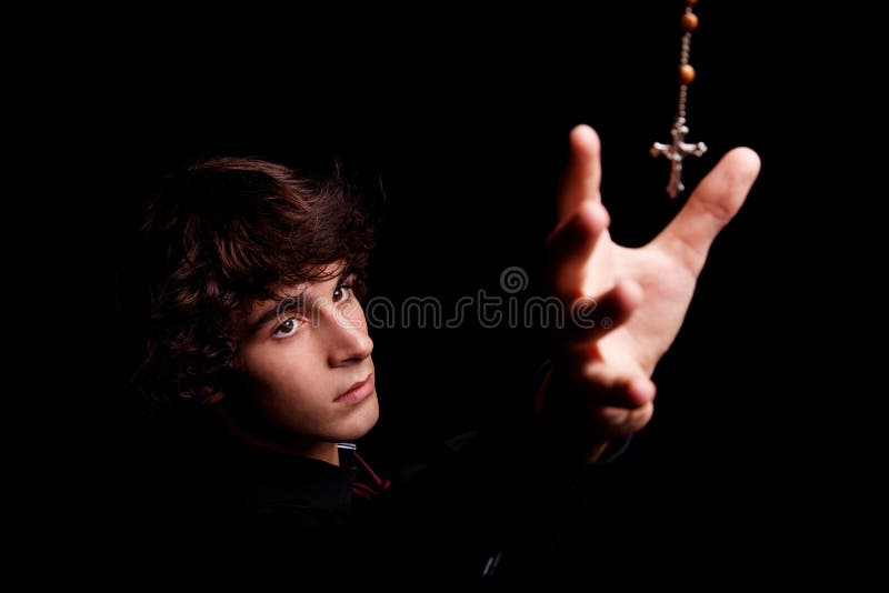 Young men with arm raised, trying to grab a crucifix, isolated on black, studio shot. Young men with arm raised, trying to grab a crucifix, isolated on black, studio shot