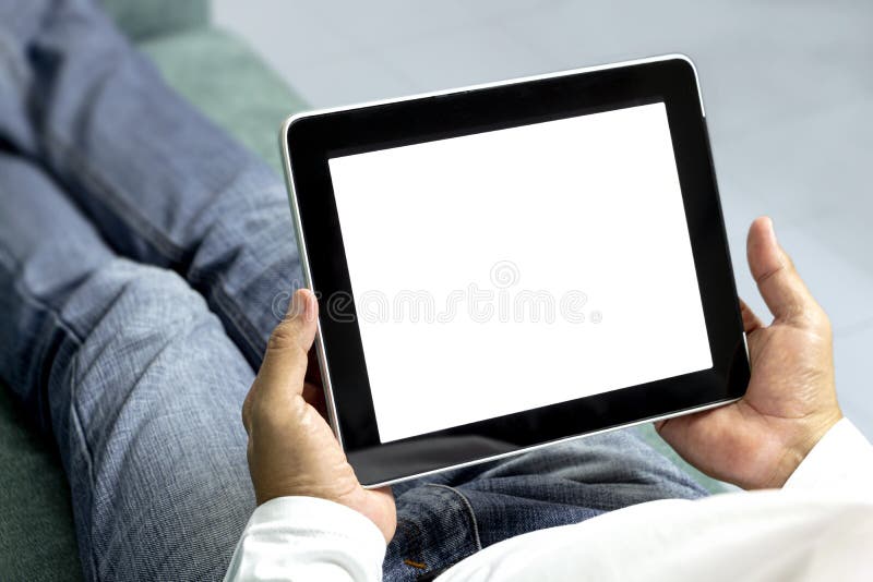 Homens sentam-se e relaxam no sofá e seguram os comprimidos móveis à mão. Tablet computer on white background e blank for your imagens de stock Homens sentam-se e relaxam no sofá e seguram os comprimidos móveis à mão. Tablet computer on white background e blank for your imagens de stock