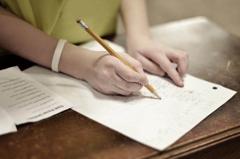 Student Holding Books And Writing In Notebook With Pencil Stock Photo