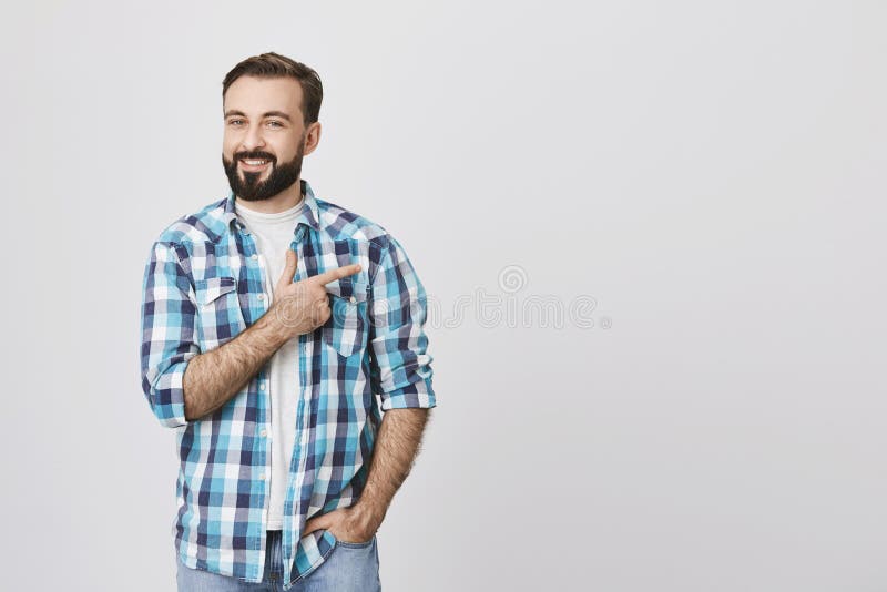 Homme adulte barbu avec du charme dans la chemise de plaid bleue se dirigeant juste avec l'index tandis qu'une autre main dans la photographie stock Homme adulte barbu avec du charme dans la chemise de plaid bleue se dirigeant juste avec l'index tandis qu'une autre main dans la photographie stock