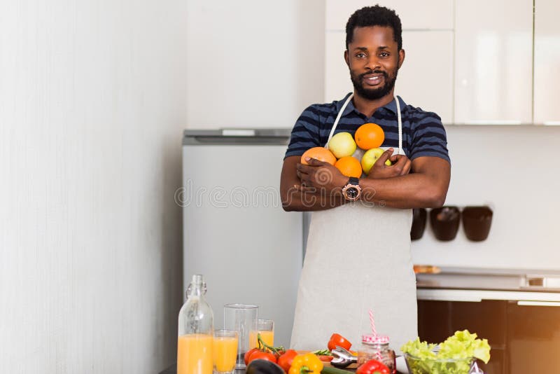 Homme africain préparant la nourriture saine à la maison dans la cuisine photographie stock Homme africain préparant la nourriture saine à la maison dans la cuisine photographie stock