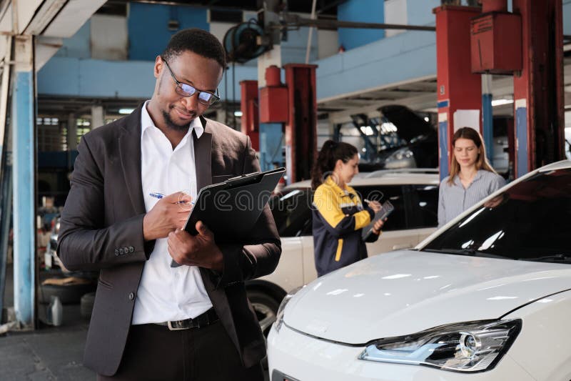 Homme agent d'assurance Noir avec un travail heureux dans un garage automobile. Homme Noir agent d'assurance en costume et lunettes avec document souriant joyeux au travail heureux service client réclamations de réparation de voiture d'affaires garantie et entretien dans l'industrie de la station de garage automobile.
