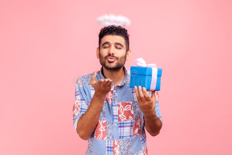 Homme angélique avec barbe en bleu casual chemise tenant dans les mains boîte présente et envoyer des baisers à air en caméra expr photographie stock libre de droits