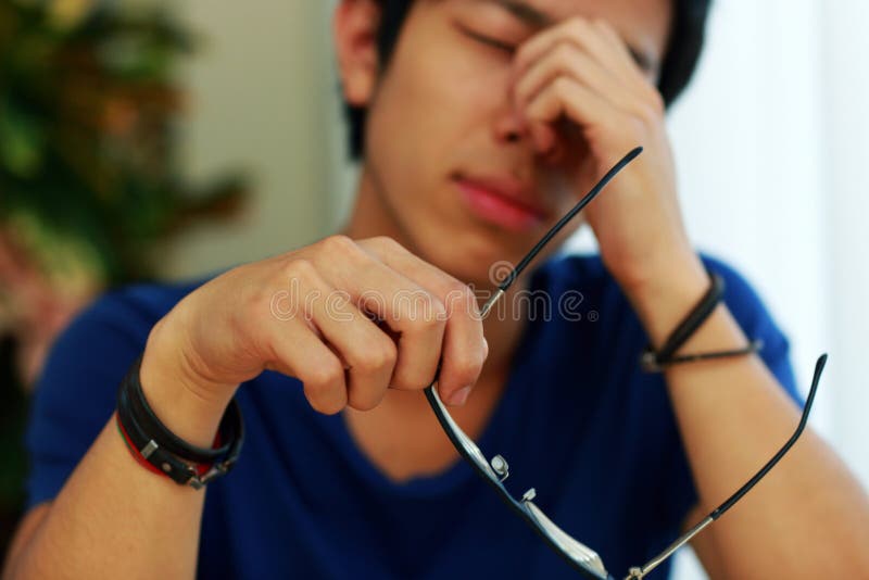 Homme asiatique avec douleur oculaire tenant des verres image stock Homme asiatique avec douleur oculaire tenant des verres image stock