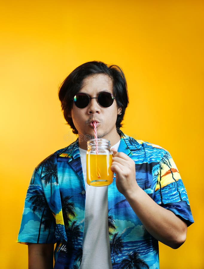 Homme asiatique buvant Juice Wearing Sunglasses orange contre Yello photos libres de droits Homme asiatique buvant Juice Wearing Sunglasses orange contre Yello photos libres de droits