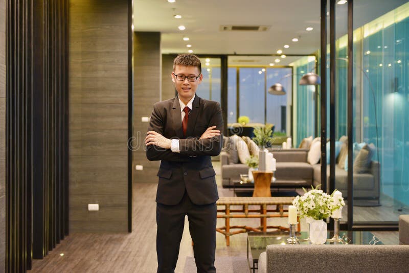 Homme asiatique d'affaires souriant devant le salon de luxe dans le mod image libre de droits Homme asiatique d'affaires souriant devant le salon de luxe dans le mod image libre de droits