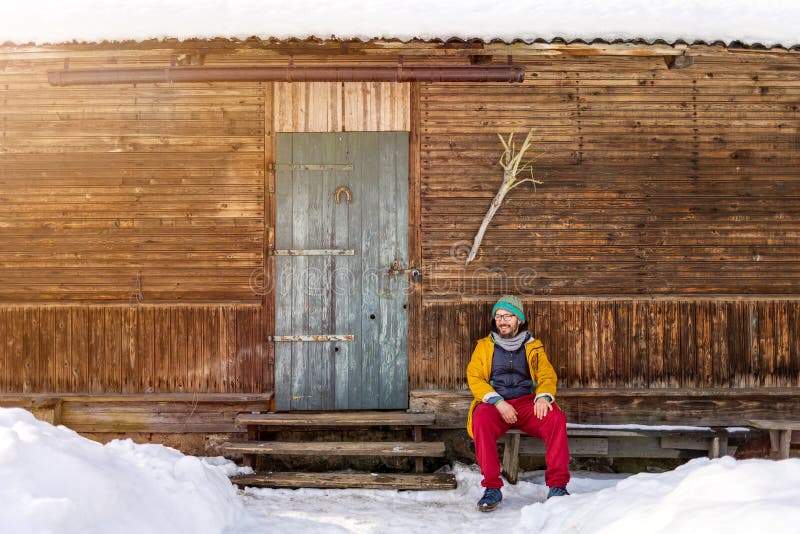 Homme assis devant la traditionnelle maison en bois photo libre de droits