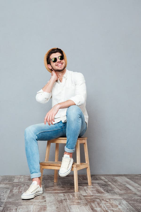Homme attirant heureux dans des lunettes de soleil se reposant et riant photo stock Homme attirant heureux dans des lunettes de soleil se reposant et riant photo stock