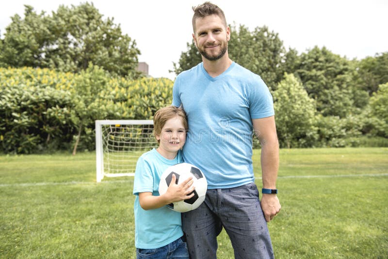 Homme avec l'enfant jouant le football dehors sur le champ photographie stock Homme avec l'enfant jouant le football dehors sur le champ photographie stock