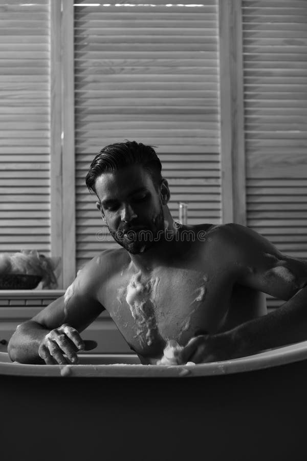 Homme avec la barbe et le visage concentré lavant avec l'éponge photo stock Homme avec la barbe et le visage concentré lavant avec l'éponge photo stock