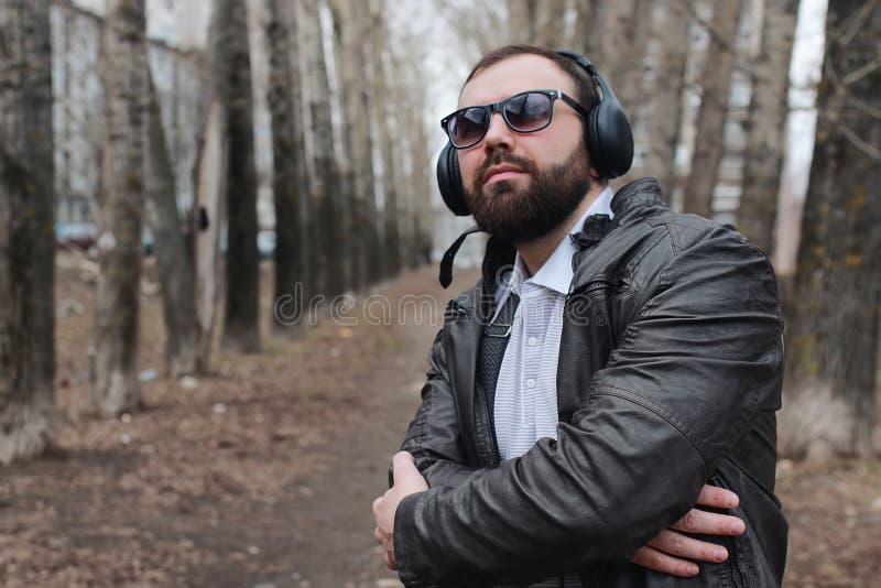 Homme avec la barbe et écouteurs en parc