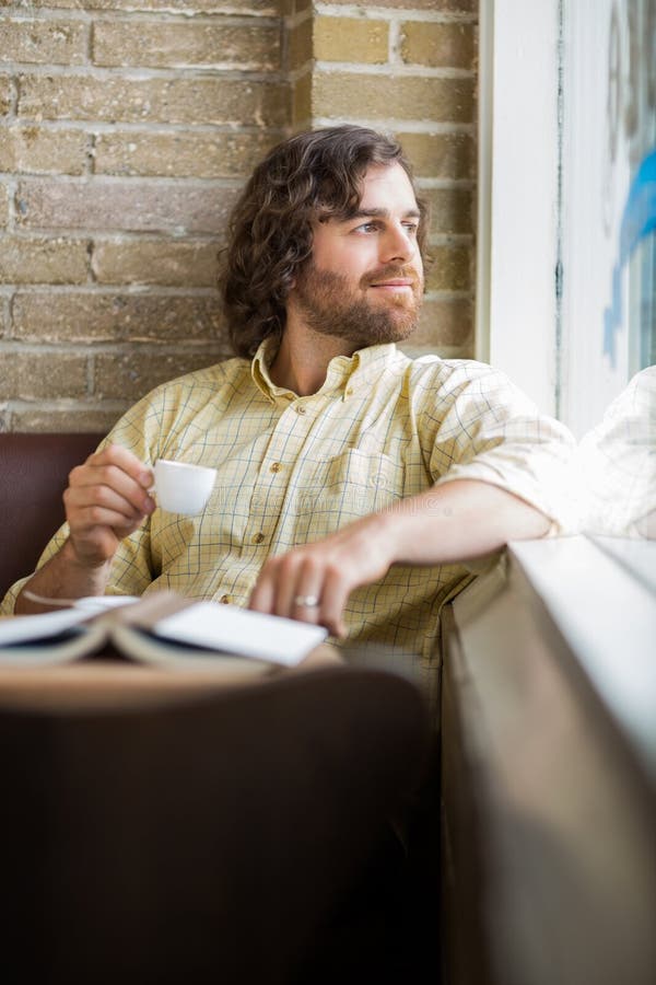 Homme avec la tasse de café regardant par la fenêtre en café photos libres de droits Homme avec la tasse de café regardant par la fenêtre en café photos libres de droits