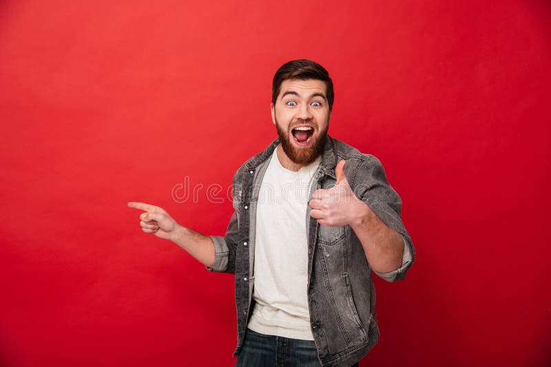 Homme avec plaisir de brune dans le clothin occasionnel montrant le pouce tandis que images libres de droits Homme avec plaisir de brune dans le clothin occasionnel montrant le pouce tandis que images libres de droits