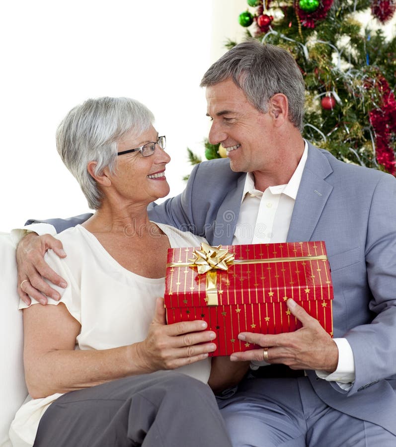 Homme aîné donnant un cadeau de Noël à son épouse images stock Homme aîné donnant un cadeau de Noël à son épouse images stock