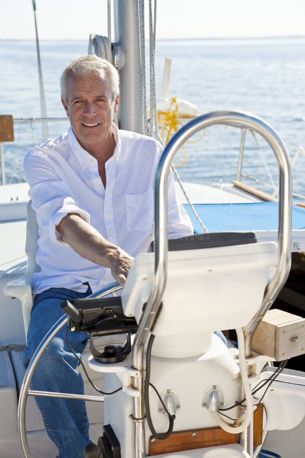 Homme aîné heureux à la roue d'un bateau à voile photographie stock libre de droits Homme aîné heureux à la roue d'un bateau à voile photographie stock libre de droits