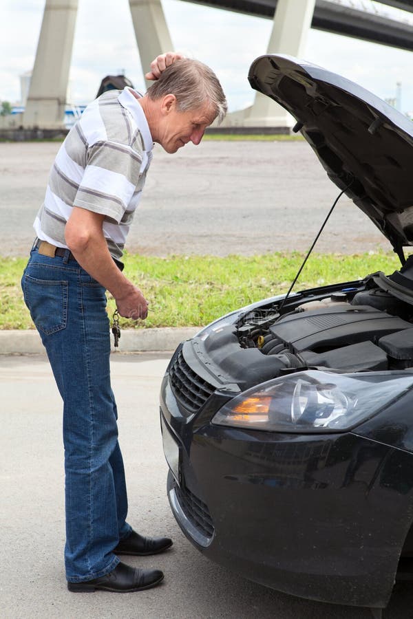 Homme aîné à une perte près d'engine de véhicule photographie stock Homme aîné à une perte près d'engine de véhicule photographie stock