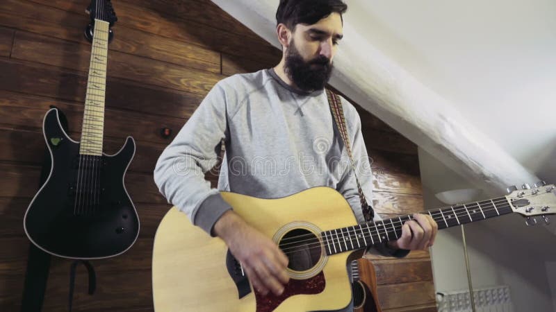 Homme barbu bel jouant le mouvement lent de guitare acoustique