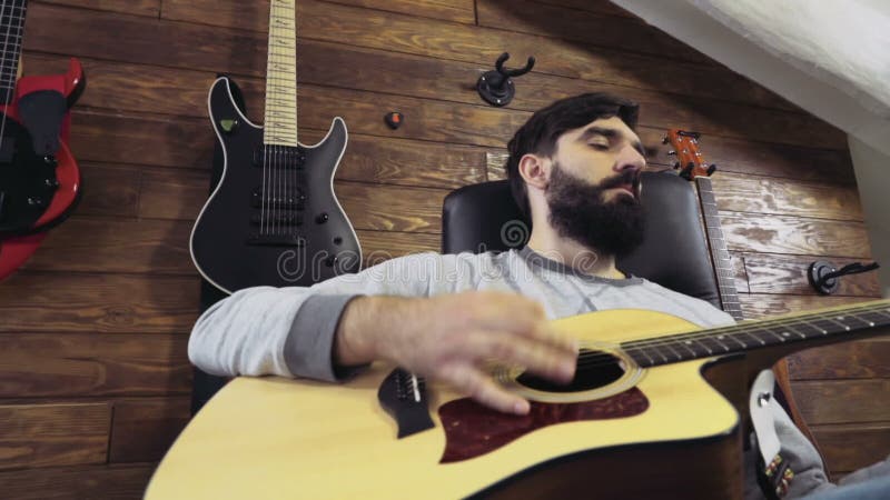 Homme barbu bel jouant le mouvement lent de guitare acoustique