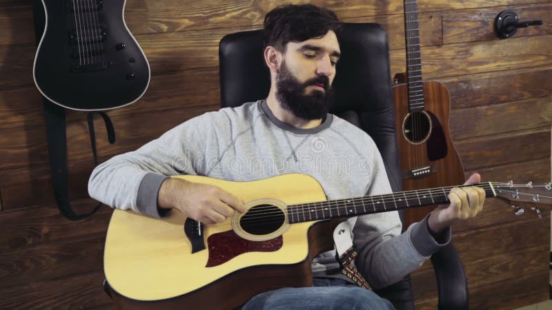 Homme barbu bel jouant le mouvement lent de guitare acoustique