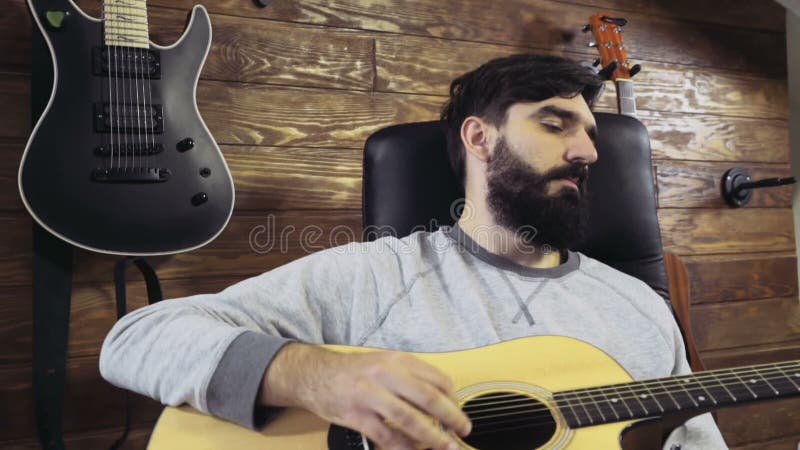 Homme barbu bel jouant le mouvement lent de guitare acoustique