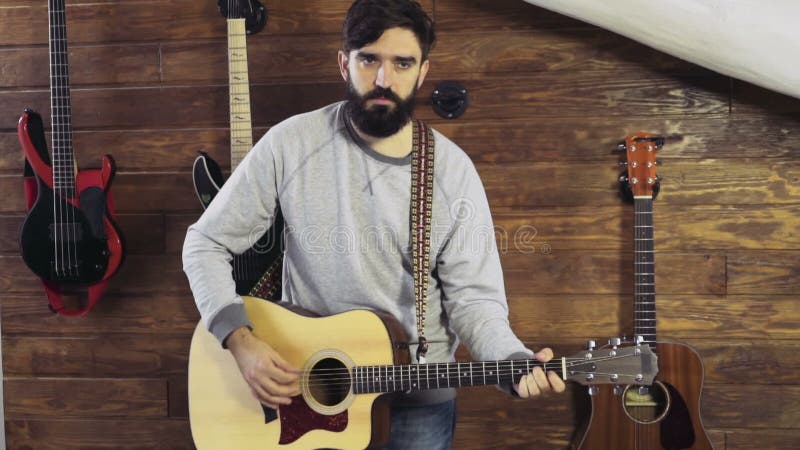 Homme barbu bel jouant le mouvement lent de guitare acoustique