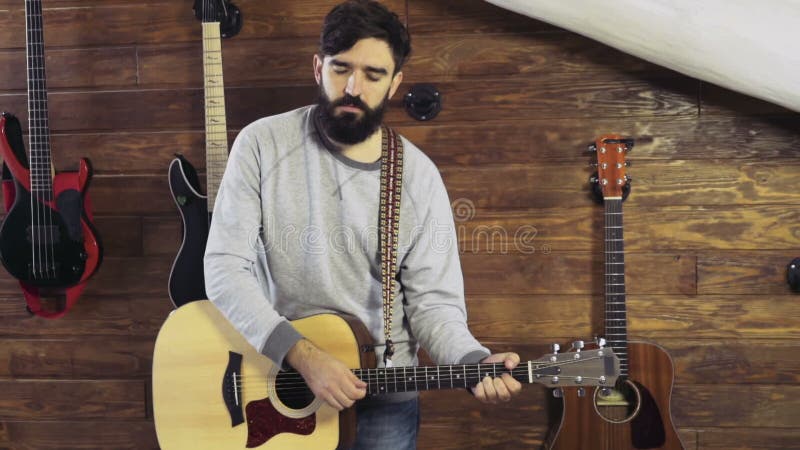 Homme barbu bel jouant le mouvement lent de guitare acoustique