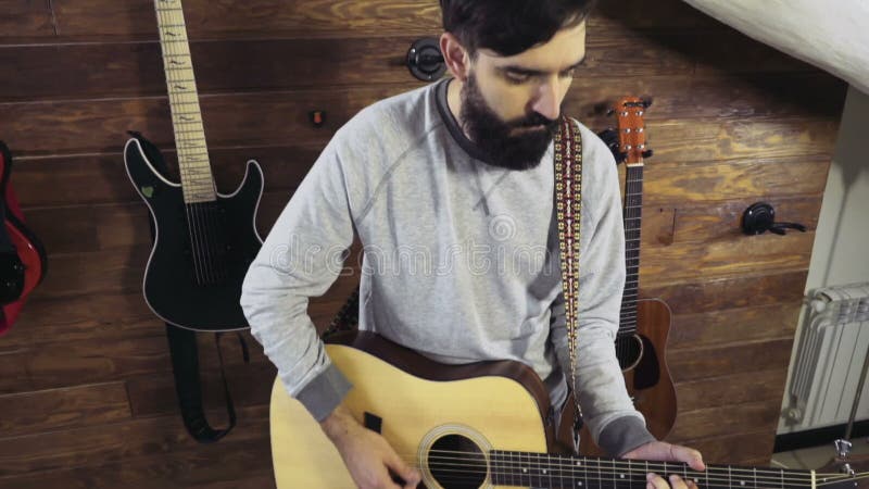 Homme barbu bel jouant le mouvement lent de guitare acoustique