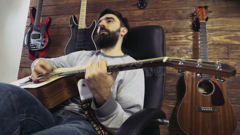 Homme barbu bel jouant le mouvement lent de guitare acoustique