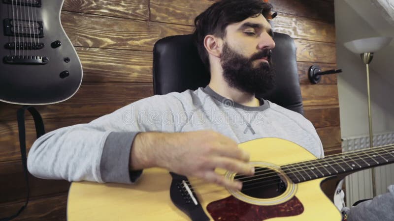 Homme barbu bel jouant le mouvement lent de guitare acoustique