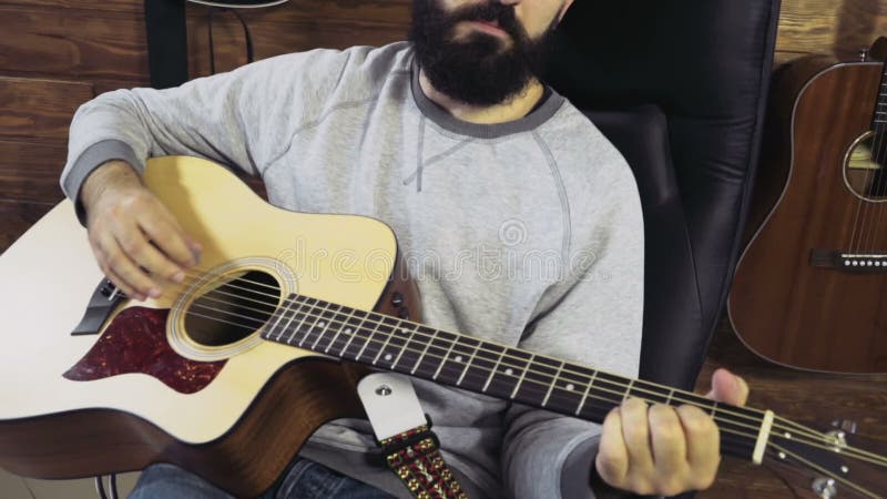 Homme barbu bel jouant le mouvement lent de guitare acoustique