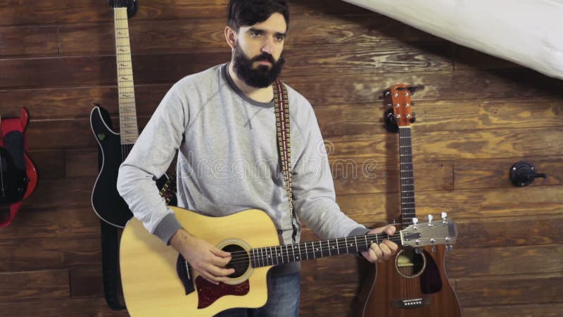 Homme barbu bel jouant le mouvement lent de guitare acoustique