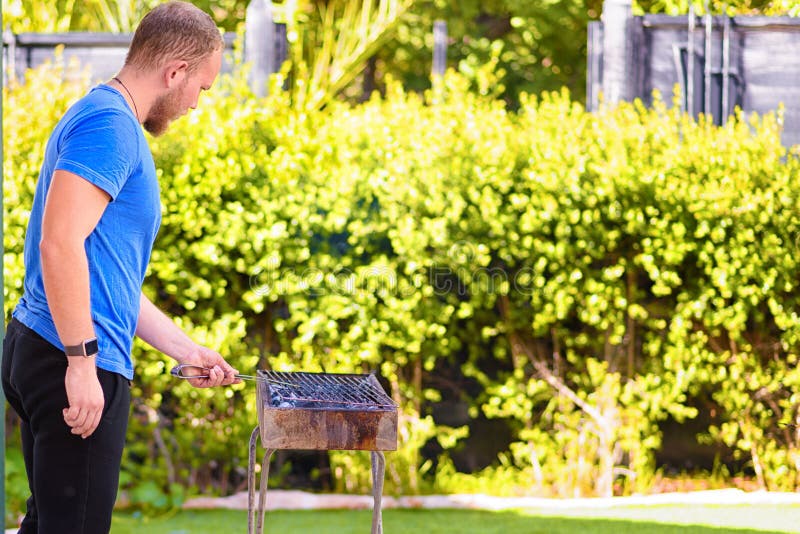 Homme barbu brutal bel faisant cuire le barbecue dehors photo libre de droits Homme barbu brutal bel faisant cuire le barbecue dehors photo libre de droits