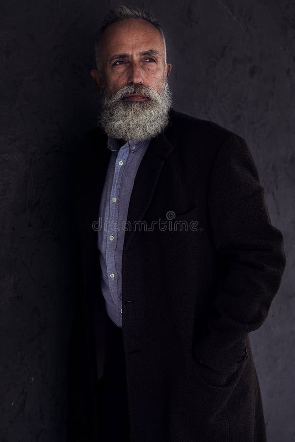 Homme barbu songeur regardant quelque part tout en posant dans le studi foncé photo libre de droits Homme barbu songeur regardant quelque part tout en posant dans le studi foncé photo libre de droits