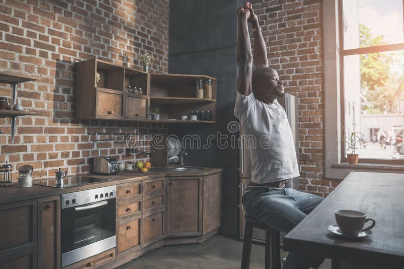 Homme bel d'afro-américain s'étirant avec le sourire agréable tout en se reposant photo stock Homme bel d'afro-américain s'étirant avec le sourire agréable tout en se reposant photo stock