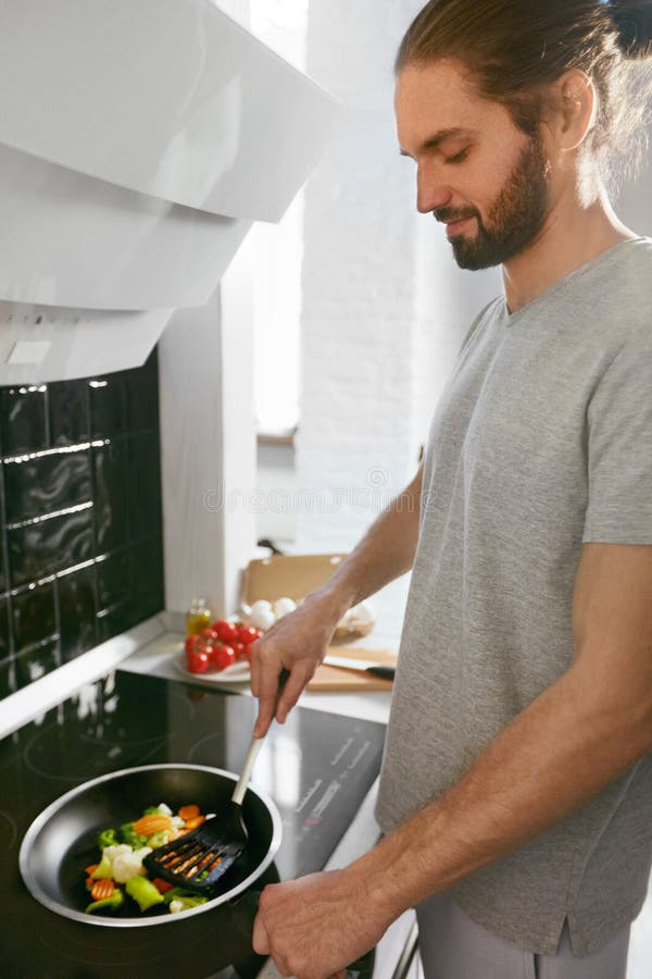 Homme bel faisant cuire le petit déjeuner à la maison dans la cuisine photographie stock libre de droits Homme bel faisant cuire le petit déjeuner à la maison dans la cuisine photographie stock libre de droits