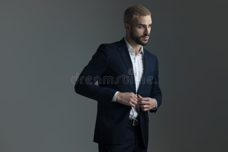 Homme blond dans le costume ajustant sa veste de salon images libres de droits Homme blond dans le costume ajustant sa veste de salon images libres de droits