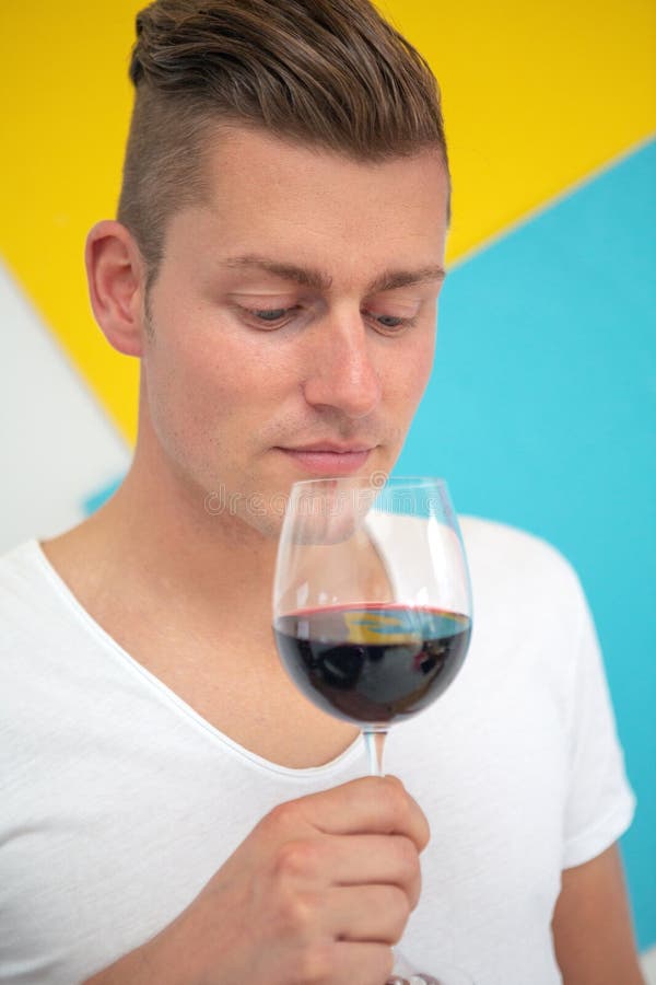 Homme blond en prenant un verre de vin rouge sur le fond coloré