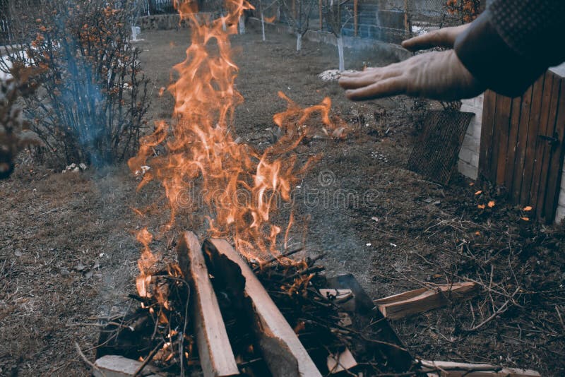 Homme caucasien chauffant ses mains au feu de camp dans une atmosphère foncée froide photo libre de droits Homme caucasien chauffant ses mains au feu de camp dans une atmosphère foncée froide photo libre de droits
