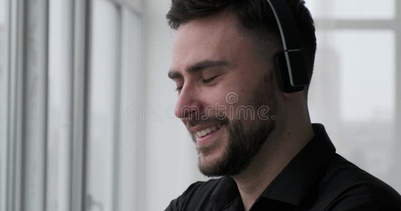 Homme caucasien en chemise noire jouant de la musique près de la fenêtre