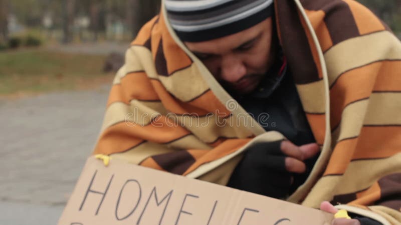 Homme congelé couvert de couverture demandant l'aumône dans la rue, phénomène des sans-abri