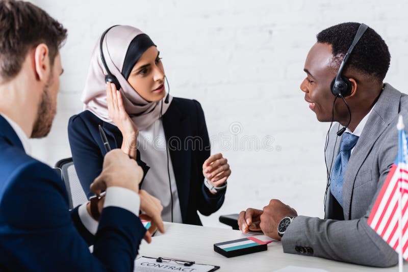 arabian and african american business partners in headsets near translator on blurred foreground. arabian and african american business partners in headsets near translator on blurred foreground