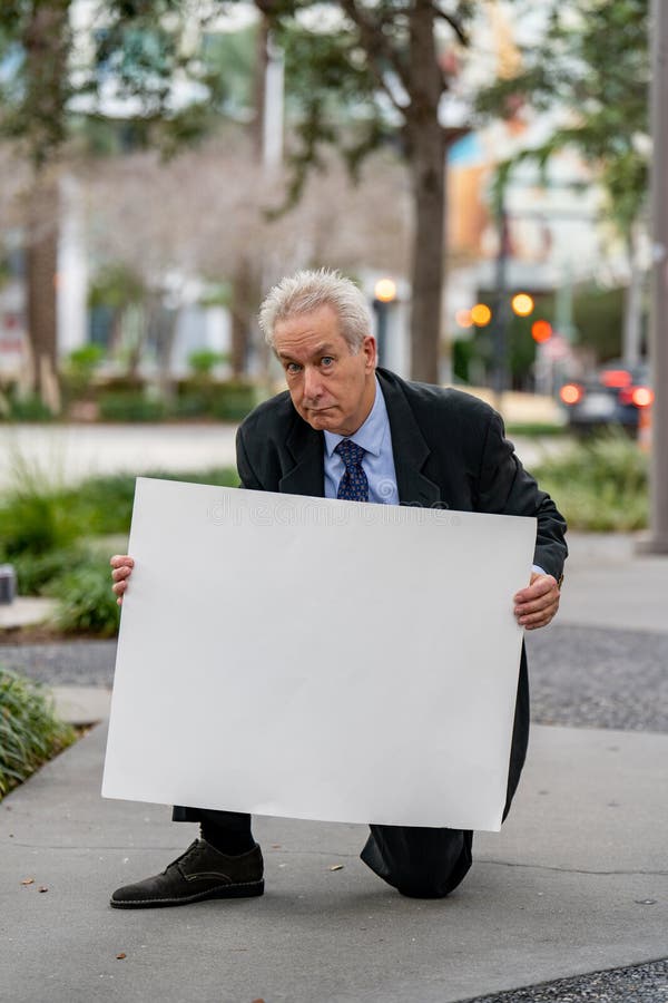 Homme d'affaires agenouillé et tenant un tableau blanc photo libre de droits