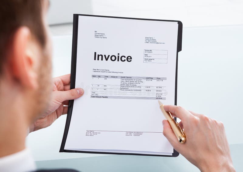 Cropped image of businessman analyzing invoice at desk in office. Cropped image of businessman analyzing invoice at desk in office