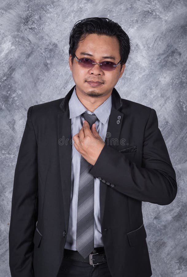 Homme d'affaires dans le costume fixant le sien lien image stock Homme d'affaires dans le costume fixant le sien lien image stock
