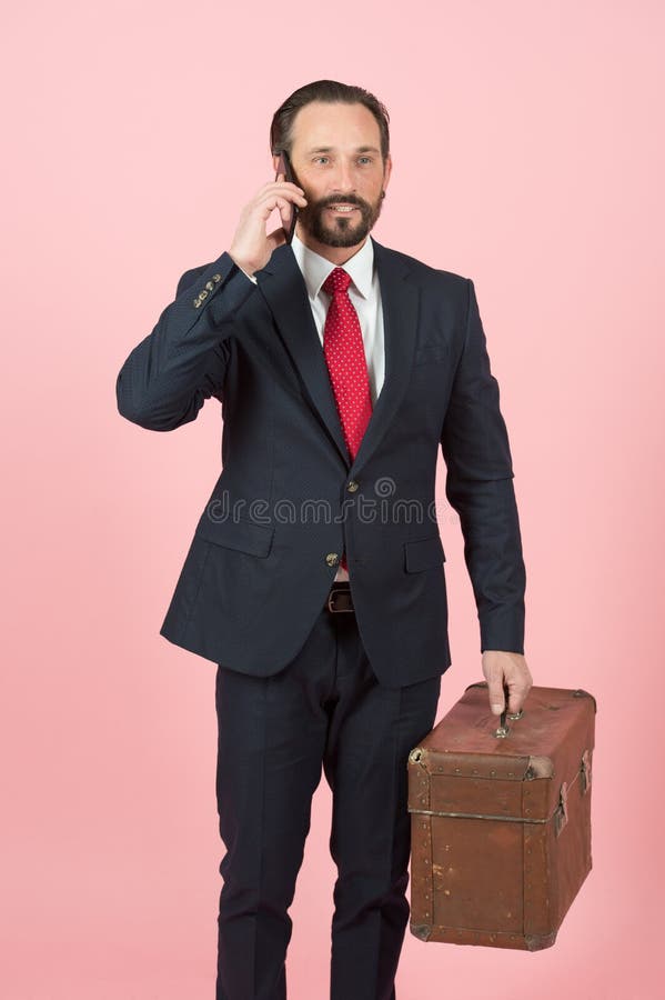 Homme d'affaires dans le costume noir et lien rouge avec la serviette de vintage parlant au-dessus du téléphone sur le fond rose photo stock Homme d'affaires dans le costume noir et lien rouge avec la serviette de vintage parlant au-dessus du téléphone sur le fond rose photo stock