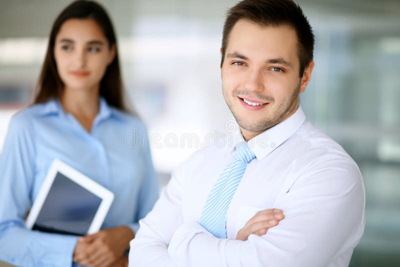 Homme d'affaires de sourire dans le bureau avec des collègues à l'arrière-plan photo stock Homme d'affaires de sourire dans le bureau avec des collègues à l'arrière-plan photo stock