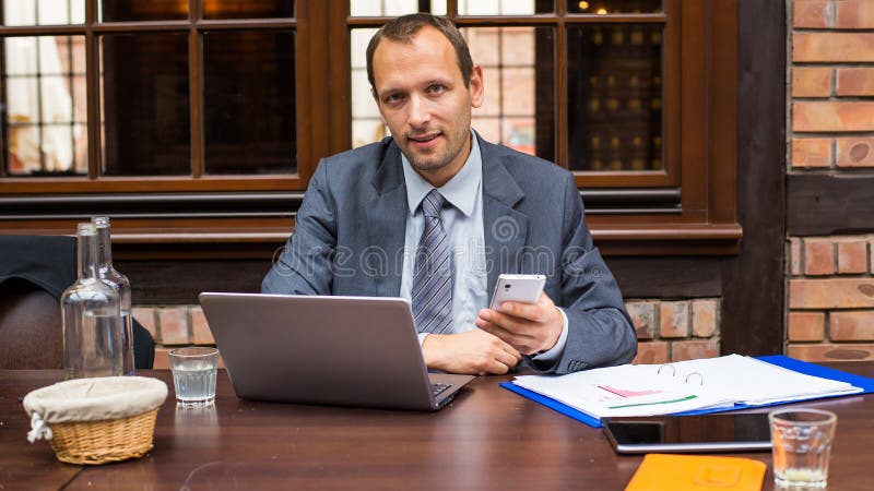 Smiling businessman making a call with his smartphone in a restaurant. Smiling businessman making a call with his smartphone in a restaurant