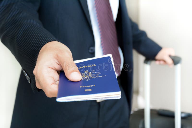 Businessman giving passport of Australia with boarding pass inside - soft focus. Businessman giving passport of Australia with boarding pass inside - soft focus