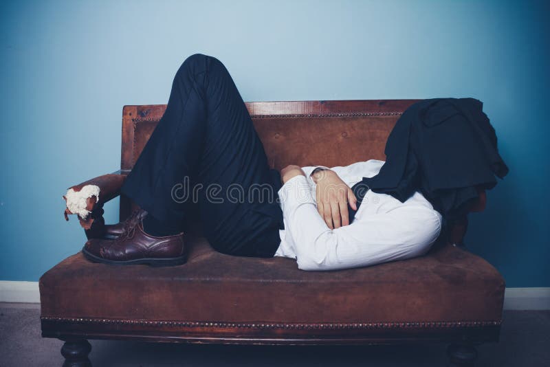 Homme d'affaires dormant sur le vieux sofa photo libre de droits Homme d'affaires dormant sur le vieux sofa photo libre de droits