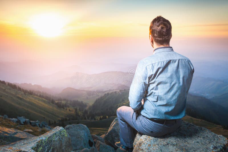 Homme d'affaires en haut de la séance et de la pensée de montagne image stock Homme d'affaires en haut de la séance et de la pensée de montagne image stock